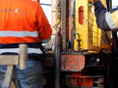 Image of people in high-visibility clothing standing in front of drilling machinery  